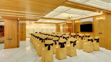 A conference room with rows of chairs, a chandelier, and a flat-screen TV.