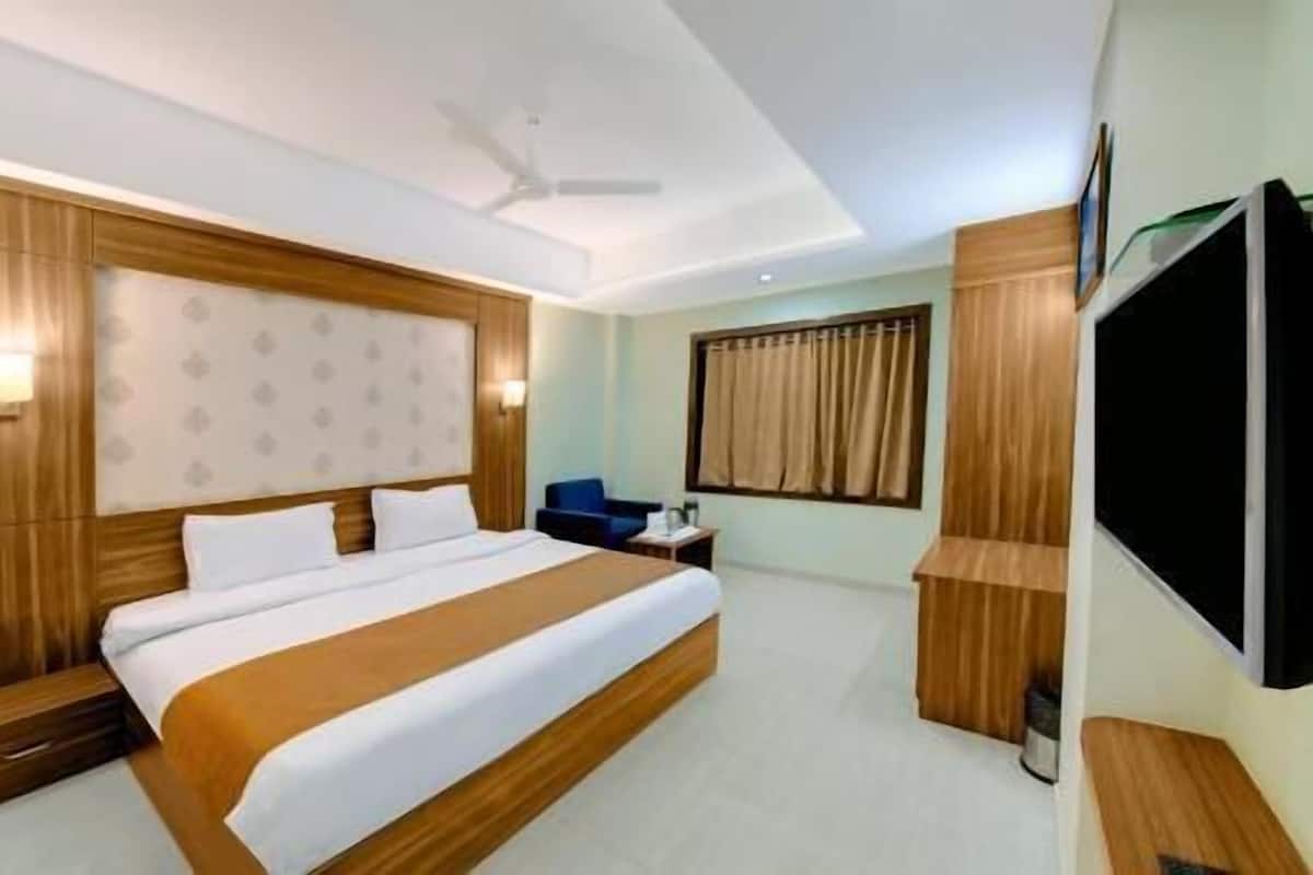 Une chambre d’hôtel avec un grand lit, une télévision, un bureau et un ventilateur de plafond.