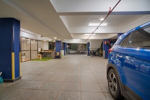 Um amplo espaço de estacionamento coberto, com um carro azul estacionado à direita.