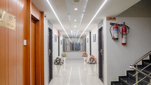 Corredor de hotel com carpete verde, paredes de madeira, placa indicando Suíte VIP 507, extintor de incêndio e escada.