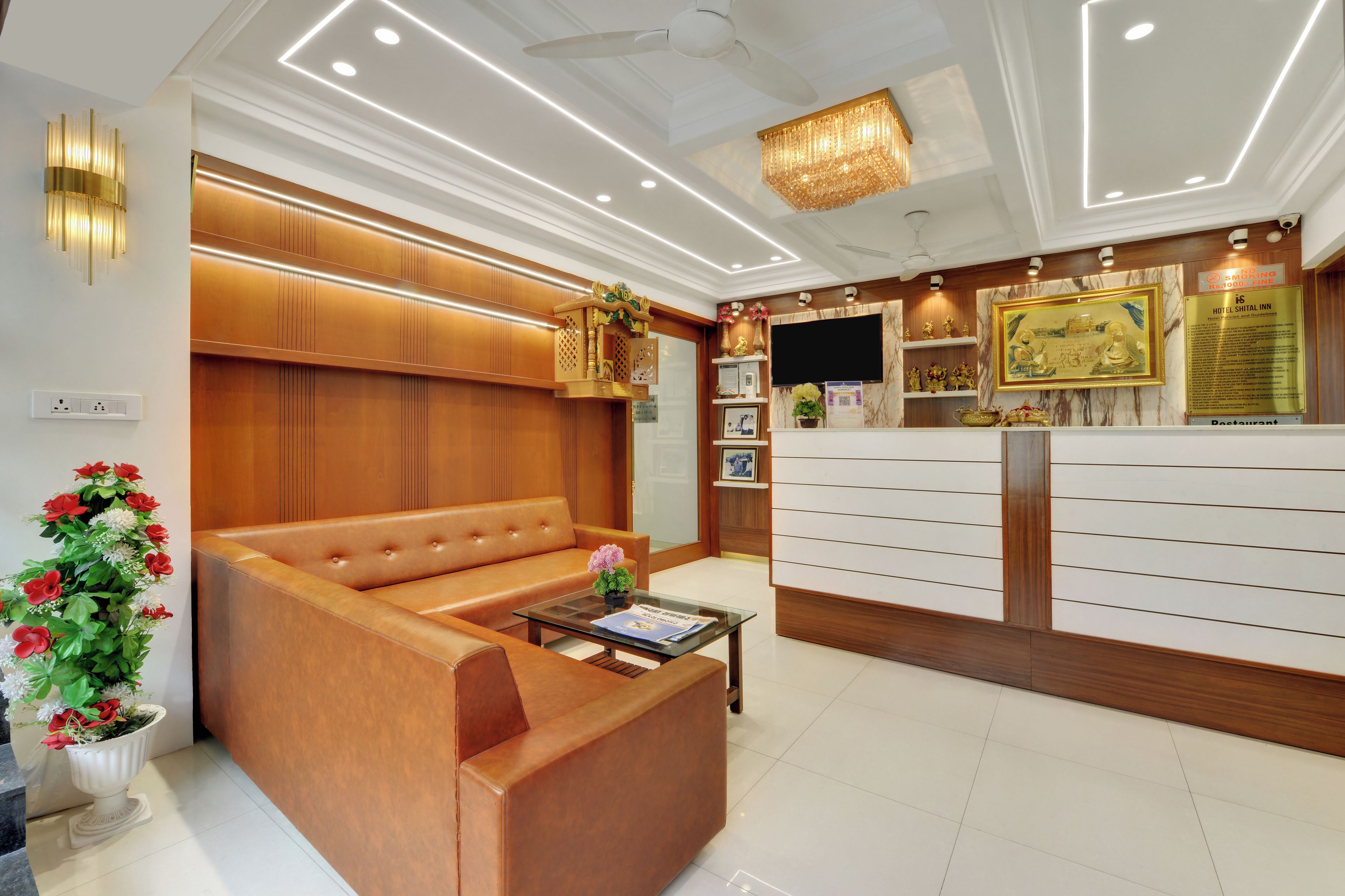 A hotel reception area with a sofa, a reception desk, and a chandelier.