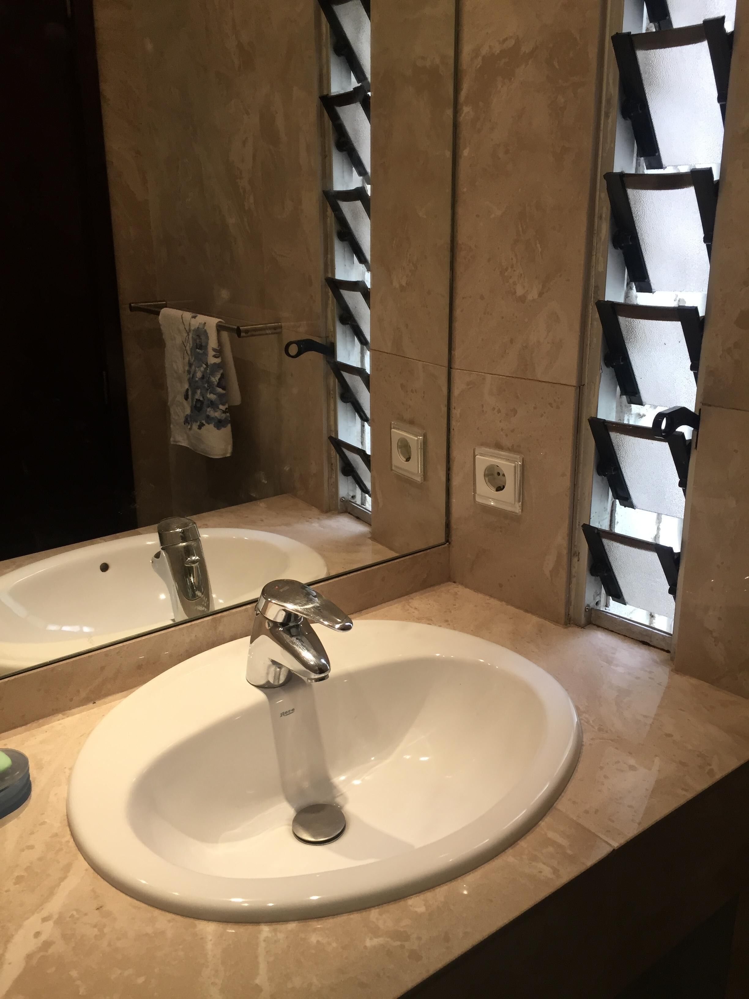 Ein Badezimmer mit einem weißen Waschbecken, einem Spiegel und einem Handtuchhalter.