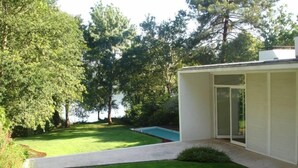 A modern house with a swimming pool, surrounded by lush greenery and trees.