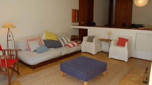 A living room with a sofa, ottoman, chairs, and a lamp.