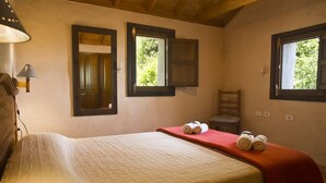 A bedroom with a bed, two windows, a chair, and a lamp.