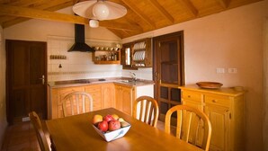 A kitchen with wooden cabinets, a dining table with chairs, and a fruit bowl.