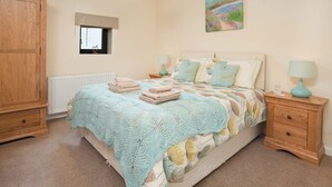 A bedroom with a bed, two bedside tables, a wardrobe, a window, and a painting on the wall.