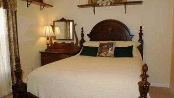 A traditional bedroom with a four-poster bed, a nightstand with a lamp, and a mirror above the bed.
