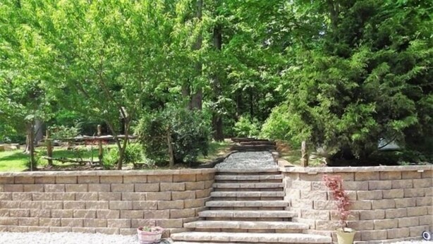 A stone staircase leading up to a wooden deck surrounded by lush greenery.