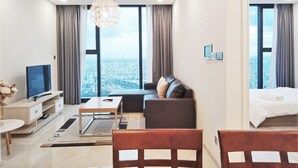 Ett modernt hotellrum med ett stort fönster som erbjuder utsikt över staden, en platt-TV, en soffa, en säng och en matplats.