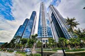 Ein modernes Hochhaus mit Glasfassade, umgeben von Grünflächen und einer Fußgängerzone.