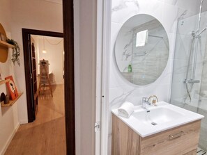 Une salle de bain moderne avec un meuble-lavabo en marbre, un miroir rond et une douche à parois de verre.