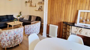 A living room with a sofa, two patterned armchairs, a coffee table, and a TV stand with decorative items.