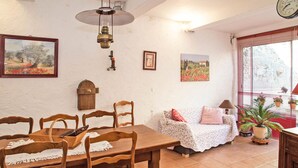Un comedor con una mesa y sillas de madera, un sofá con funda floral y un reloj de pared.