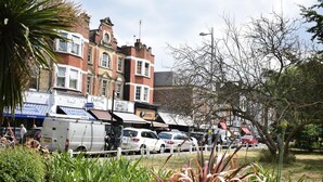 A street with parked cars and a building with a sign that reads "Osteria." - Magma Flat (London)