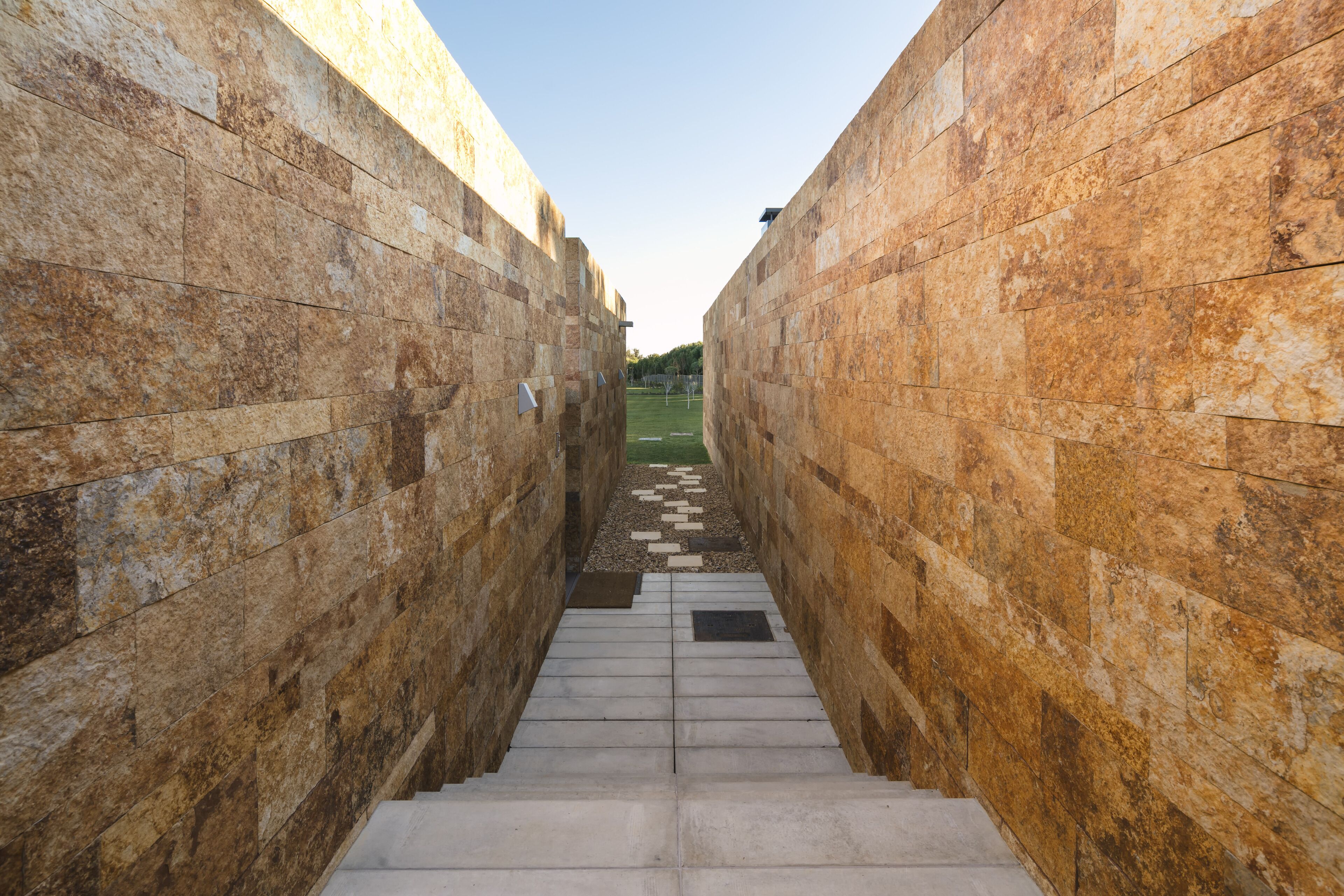 A narrow stone corridor with steps leading to a higher level.