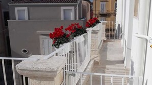 A narrow balcony with a white metal railing, a stone balustrade, and red flowers. - Il Borgo B&B (Corato)
