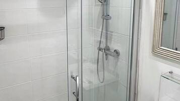 A modern bathroom with a glass-enclosed shower, a white sink, and a mirror above the sink.