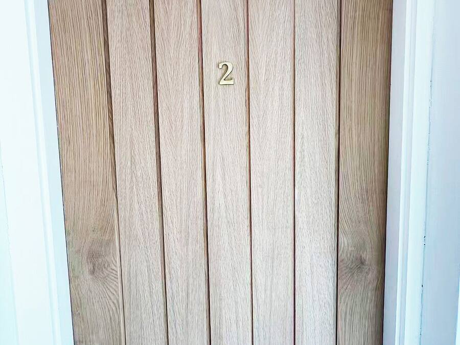 Una puerta de madera con una placa de latón con el número '2' y un picaporte.