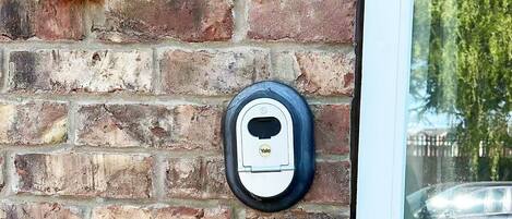 A brick wall with a Yale deadbolt lock and a metal intercom system.
