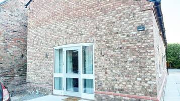 Un edificio de ladrillo con una puerta blanca y una pequeña señal encima.