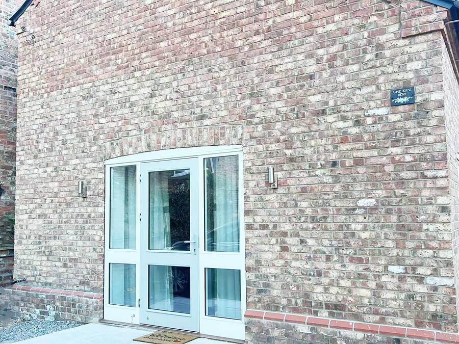 Un edificio de ladrillo con una puerta blanca y una pequeña señal encima.