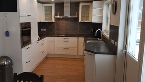 A compact kitchen with white cabinets, a black countertop, and a wooden floor. - Fantastic nature, hot tub, boat, sauna (Olofström / Gränum)