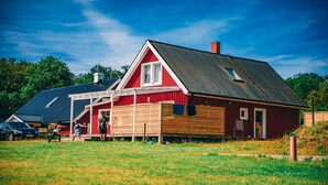 A red barn with a sloped roof and a wooden deck in front. - Fantastic nature, hot tub, boat, sauna (Olofström / Gränum)