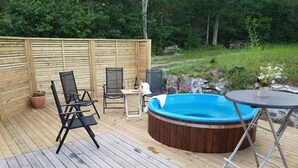 An outdoor deck with a hot tub, wooden chairs, a table, and a potted plant. - Fantastic nature, hot tub, boat, sauna (Olofström / Gränum)