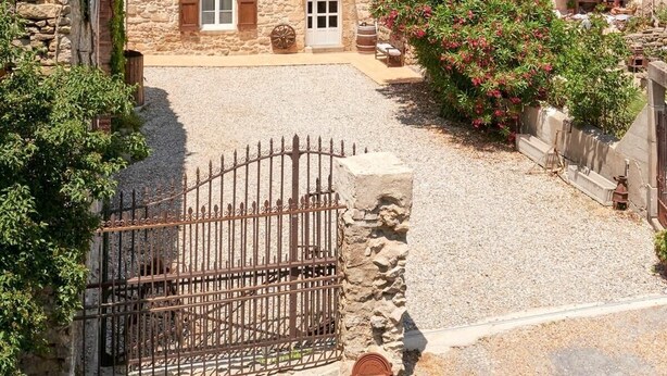 A stone building with a tiled roof, a central entrance, and a gravel courtyard. - Gîte Le Couvent    . (Cité de Carcassonne)