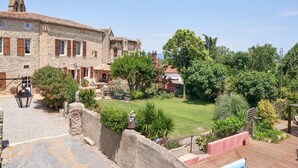A stone building with a tiled roof, a garden with various plants, and a wooden deck. - Gîte Le Couvent    . (Cité de Carcassonne)