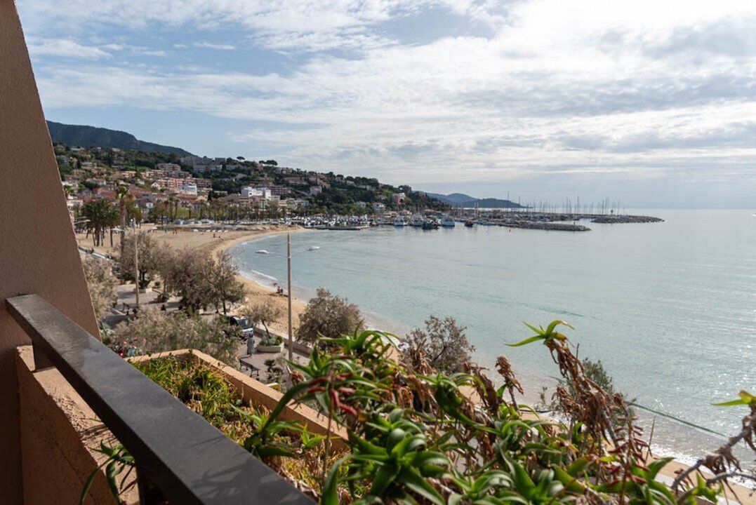 Un pueblo costero con playa, barcos y un muelle a lo lejos.