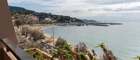 A coastal town with a beach, boats, and a distant pier.