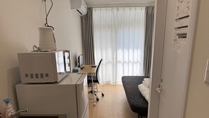 A hotel room with a kitchenette, a bed, a desk with a computer, and a large window with curtains. - Today's Bright and Cozy Room, Near Shibuya! (Setagaya)