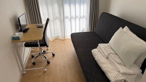 A room with a desk, chair, and a dark-colored sofa with pillows. - Today's Bright and Cozy Room, Near Shibuya! (Setagaya)