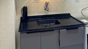 Eine Küche mit schwarzer Arbeitsplatte, einem Spülbecken und einem Schrank darüber.