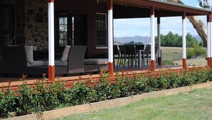 A covered outdoor seating area with stone walls, wooden deck, and a view of the landscape. - Fabulous Country Stay on cattle & sheep property northern NSW (Matheson)
