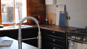 A kitchen with a stainless steel faucet, wooden cabinets, a stove, and a window with a view of a building outside. - Fabulous Country Stay on cattle & sheep property northern NSW (Matheson)