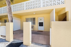 A two-story building with a balcony, a door with a window, and a small table.