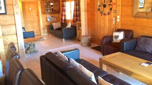A cozy log cabin interior with a living room, a dining area, and a kitchen.
