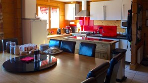 A kitchen with a dining area, wooden beams, a refrigerator, a stove, and a microwave.