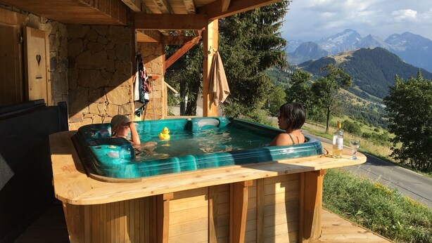 A wooden hot tub with a view of mountains.