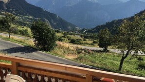 A view from a balcony overlooking a mountainous landscape with a road and trees. - Mountain Chalet (Huez)
