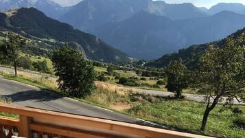 A view from a balcony overlooking a mountainous landscape with a road and trees.