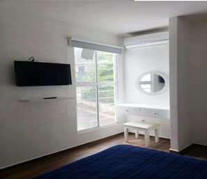 Relax in this cozy room with a large window, flat-screen TV, and comfortable dark blue bedspread.