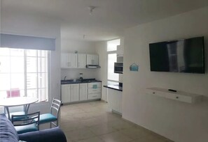 Cozy living space with kitchenette, dining area, and living room, featuring a flat-screen TV and comfortable seating.