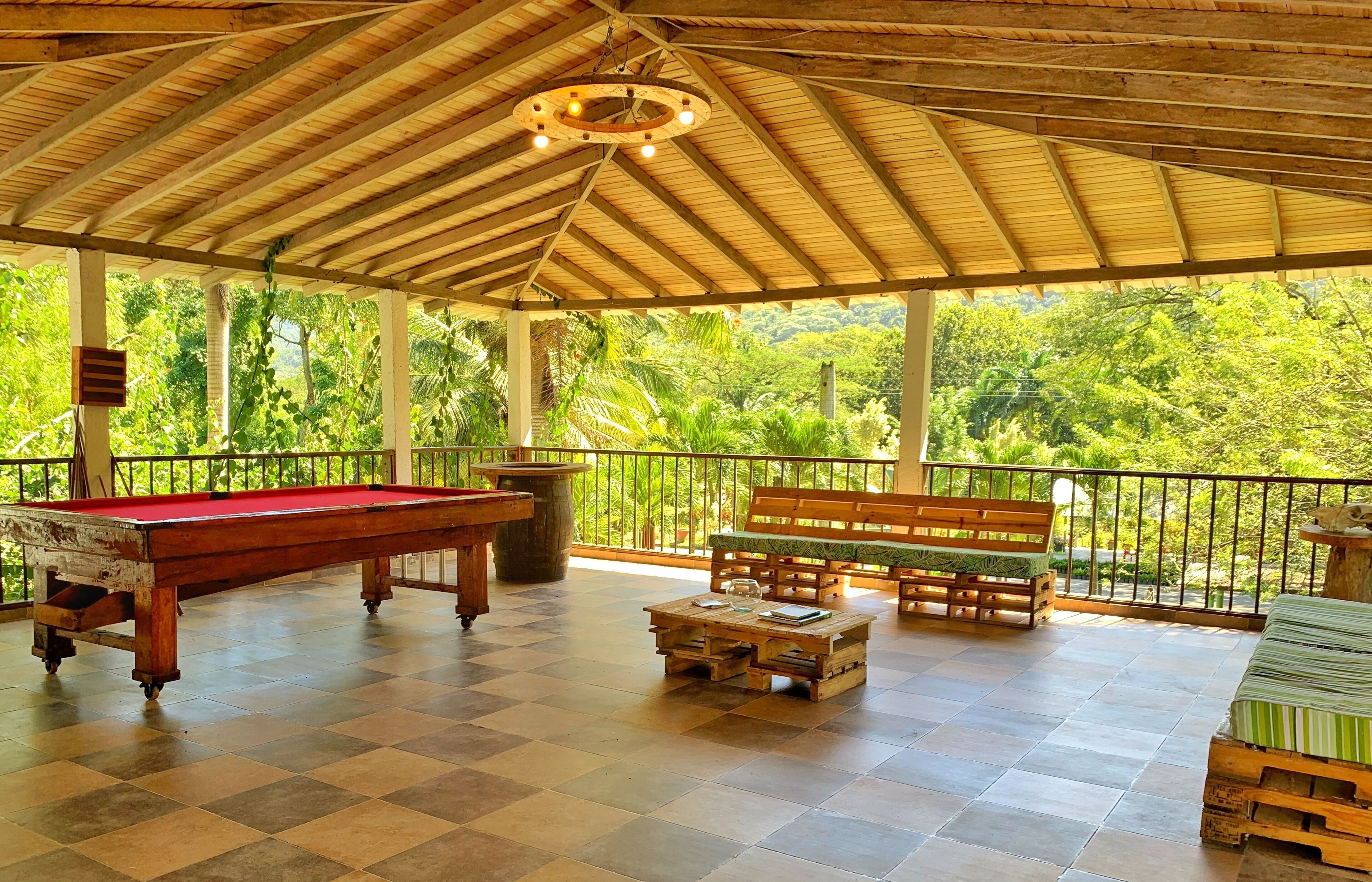 A covered outdoor area with a pool table, a wooden bench, and a coffee table.