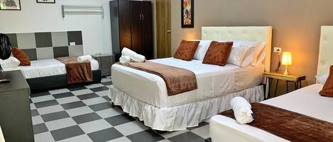 Ein Hotelzimmer mit zwei Betten, einem Schachbrettmuster-Boden, einem Kleiderschrank, einem Schreibtisch und einer Wand-Klimaanlage.