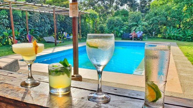 Zona de bar con vista a la piscina, con tres vasos de bebidas.