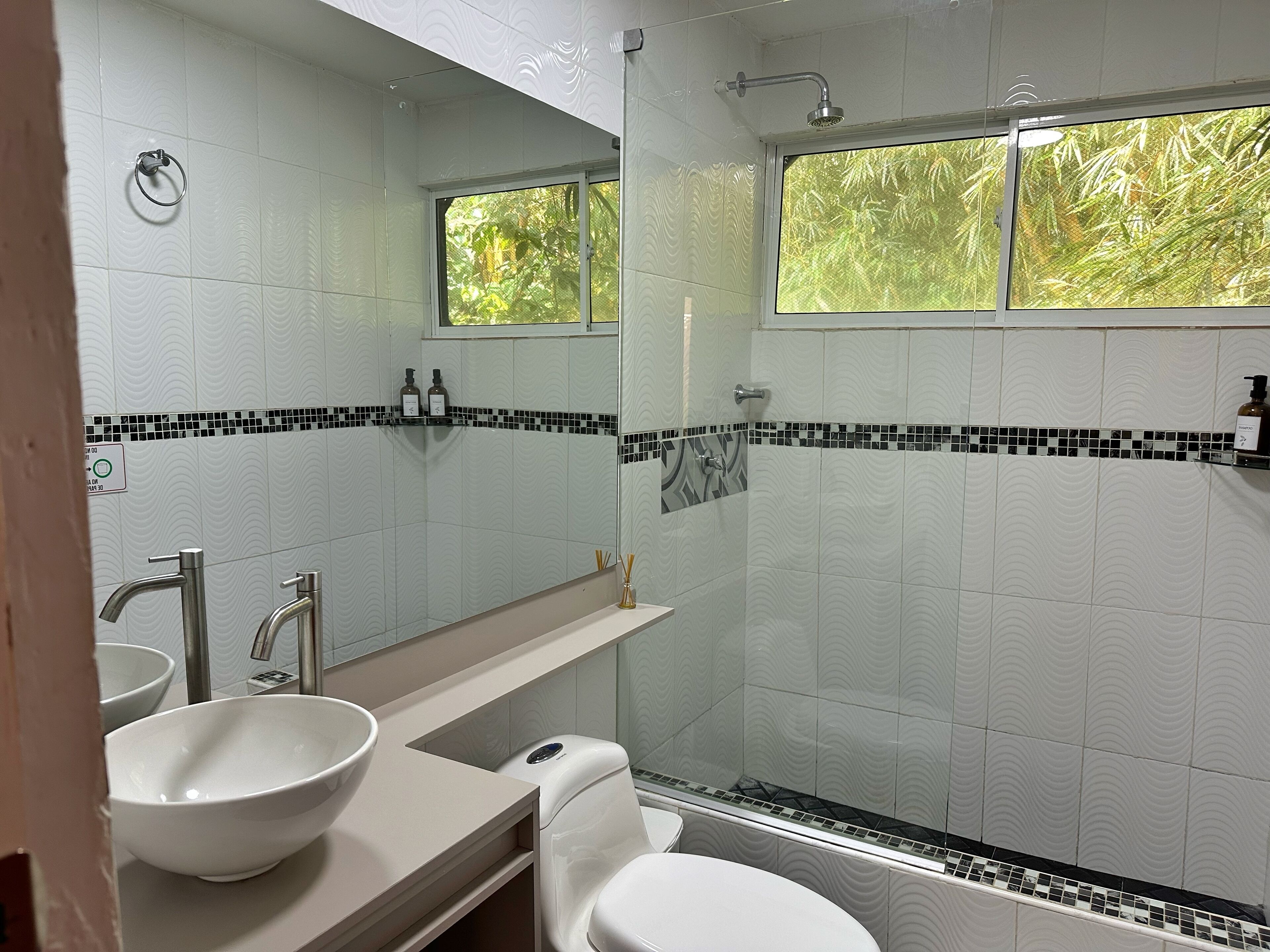 Un baño con lavamanos blanco, un espejo, inodoro y ducha.